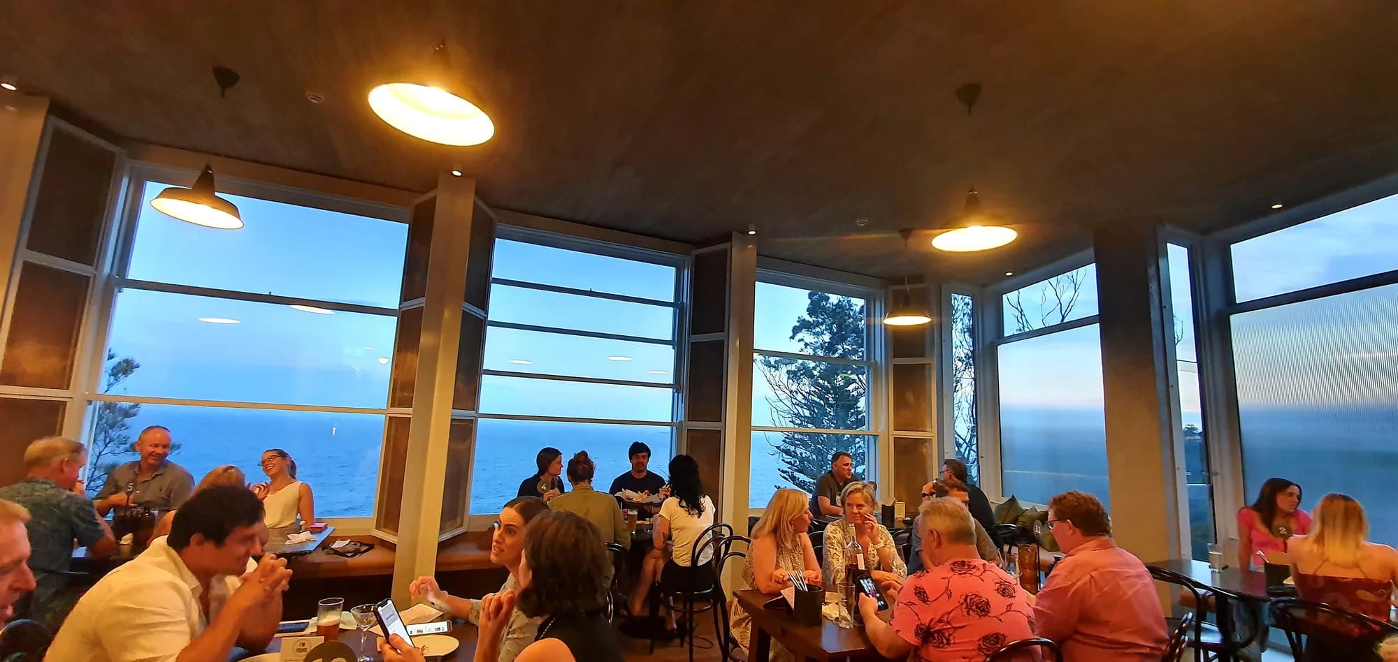 A full dining room at the Imperial at Clifton, its curved wall of windows looking out to sea