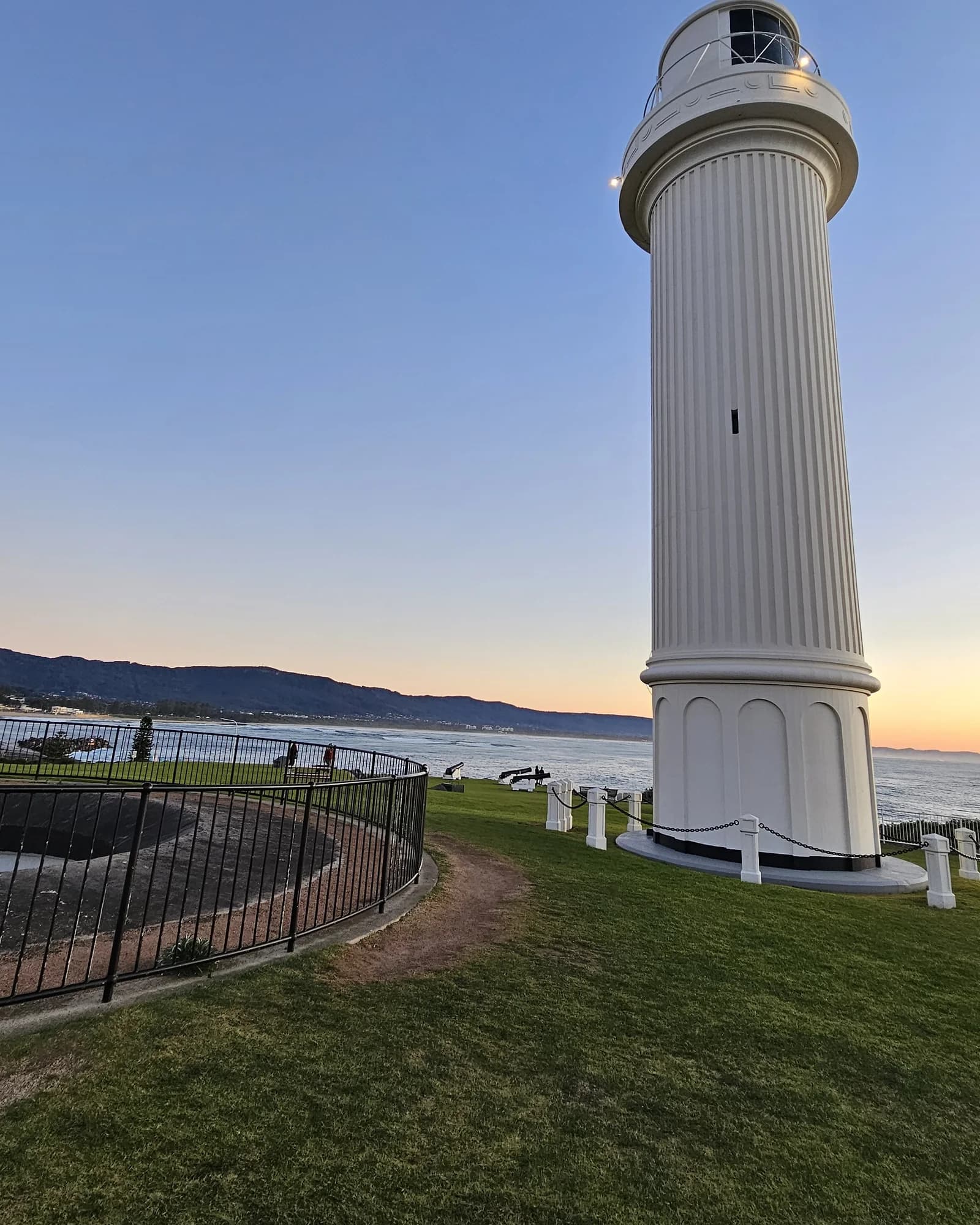The fluted white tower of Flagstaff Point Lighthouse against a clear dawn sky