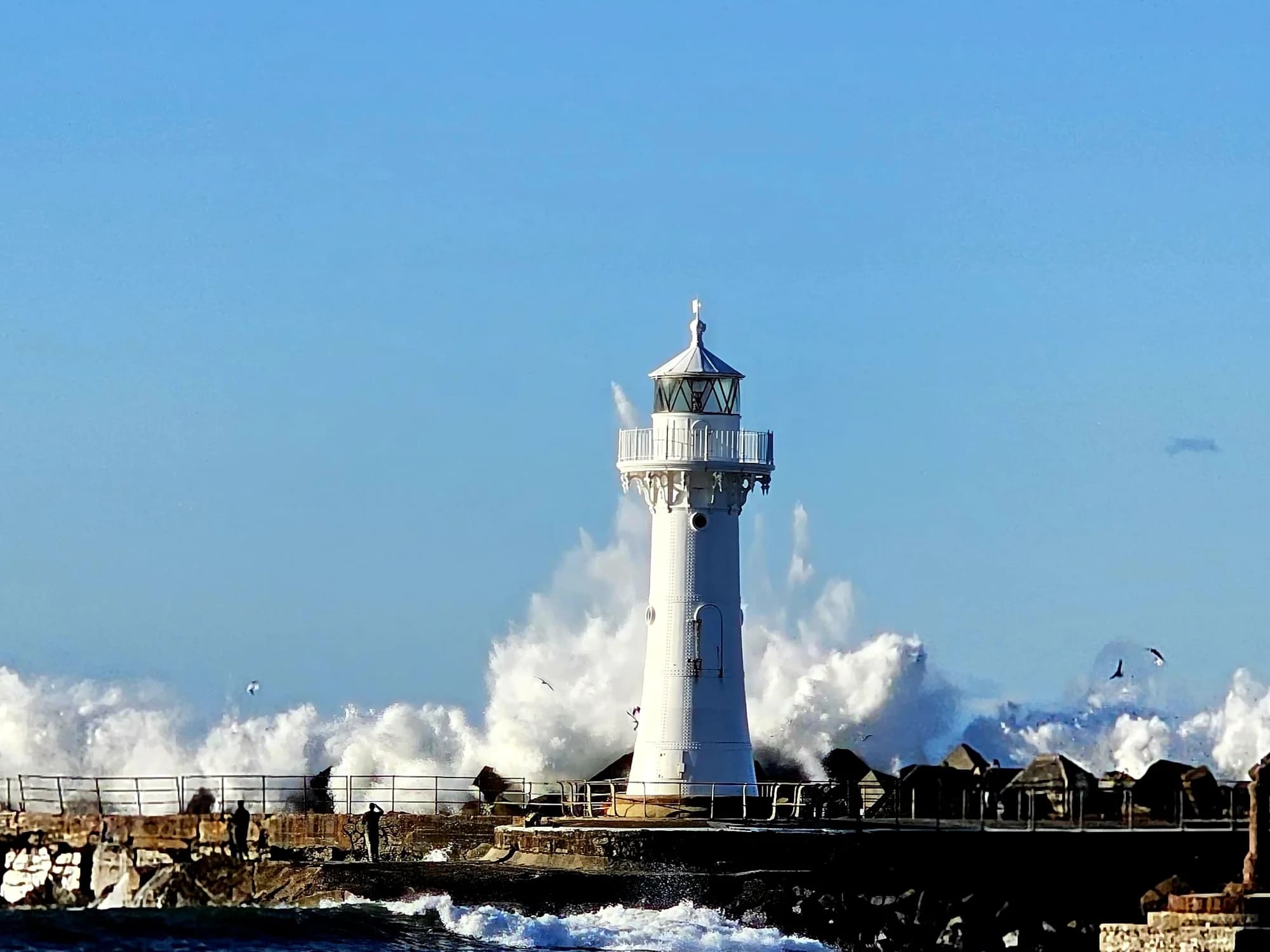 Waves exploding over the Breakwater Lighthouse at the mouth of Wollongong Harbour