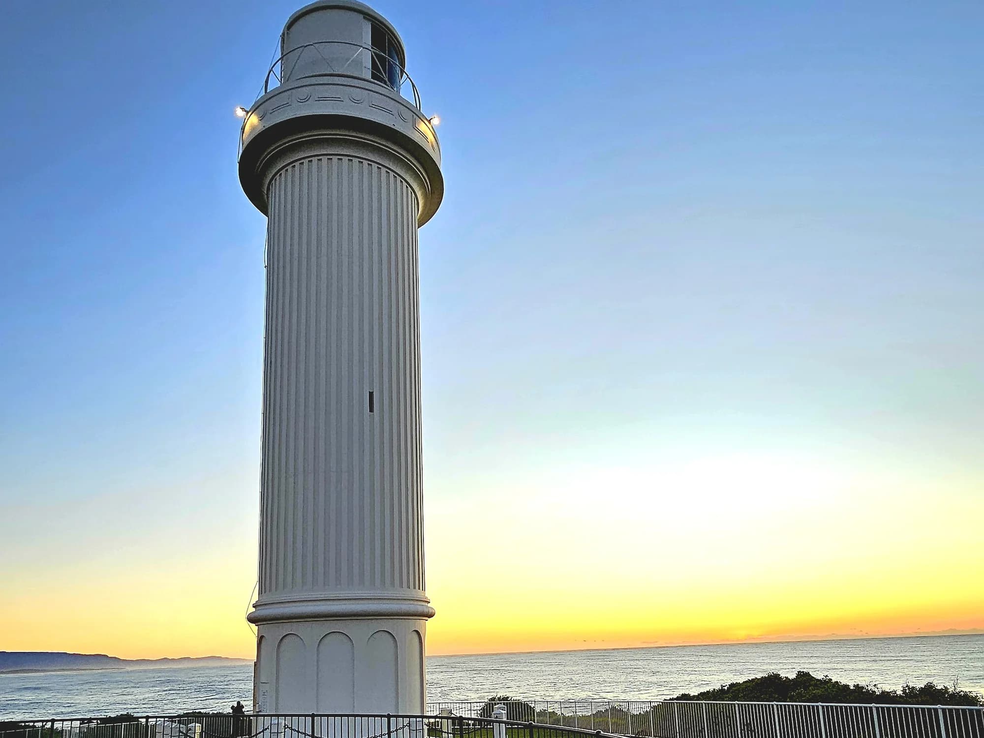 Flagstaff Point Lighthouse at dawn, the horizon turning gold behind it