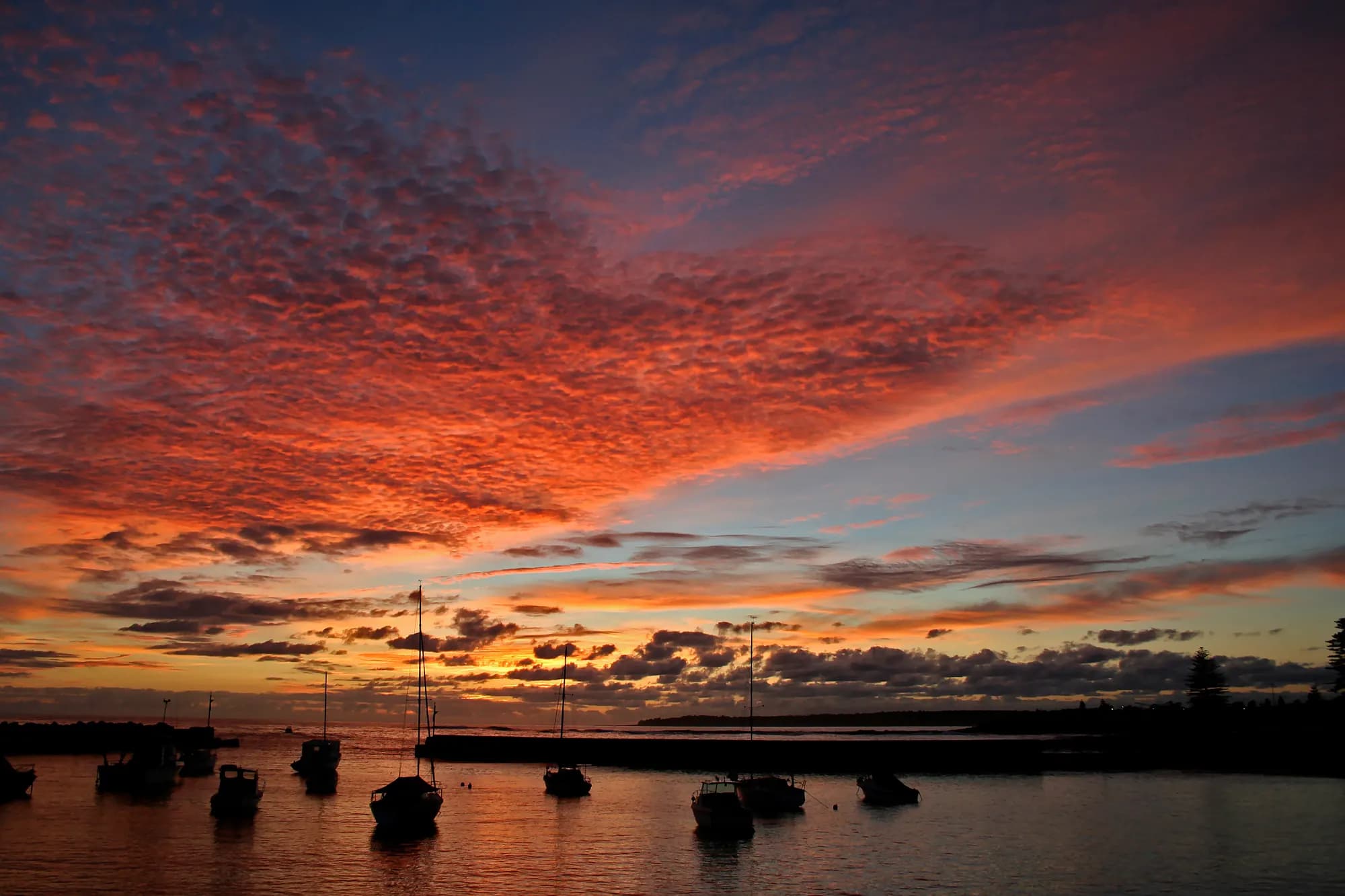 A red dawn sky over boats moored in Shellharbour's harbour